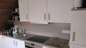 Uma cozinha moderna com eletrodomésticos de aço inoxidável, armários brancos e um relógio digital mostrando 2:29.