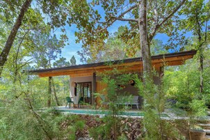 Una casa moderna con terraza de madera, rodeada de árboles y una piscina.