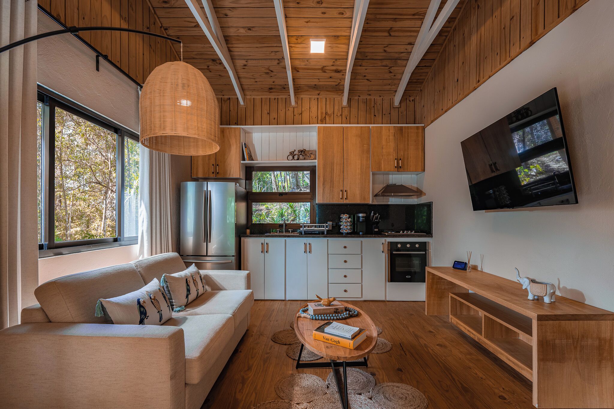 Una cocina moderna con armarios de madera, horno empotrado y un televisor grande montado en la pared.