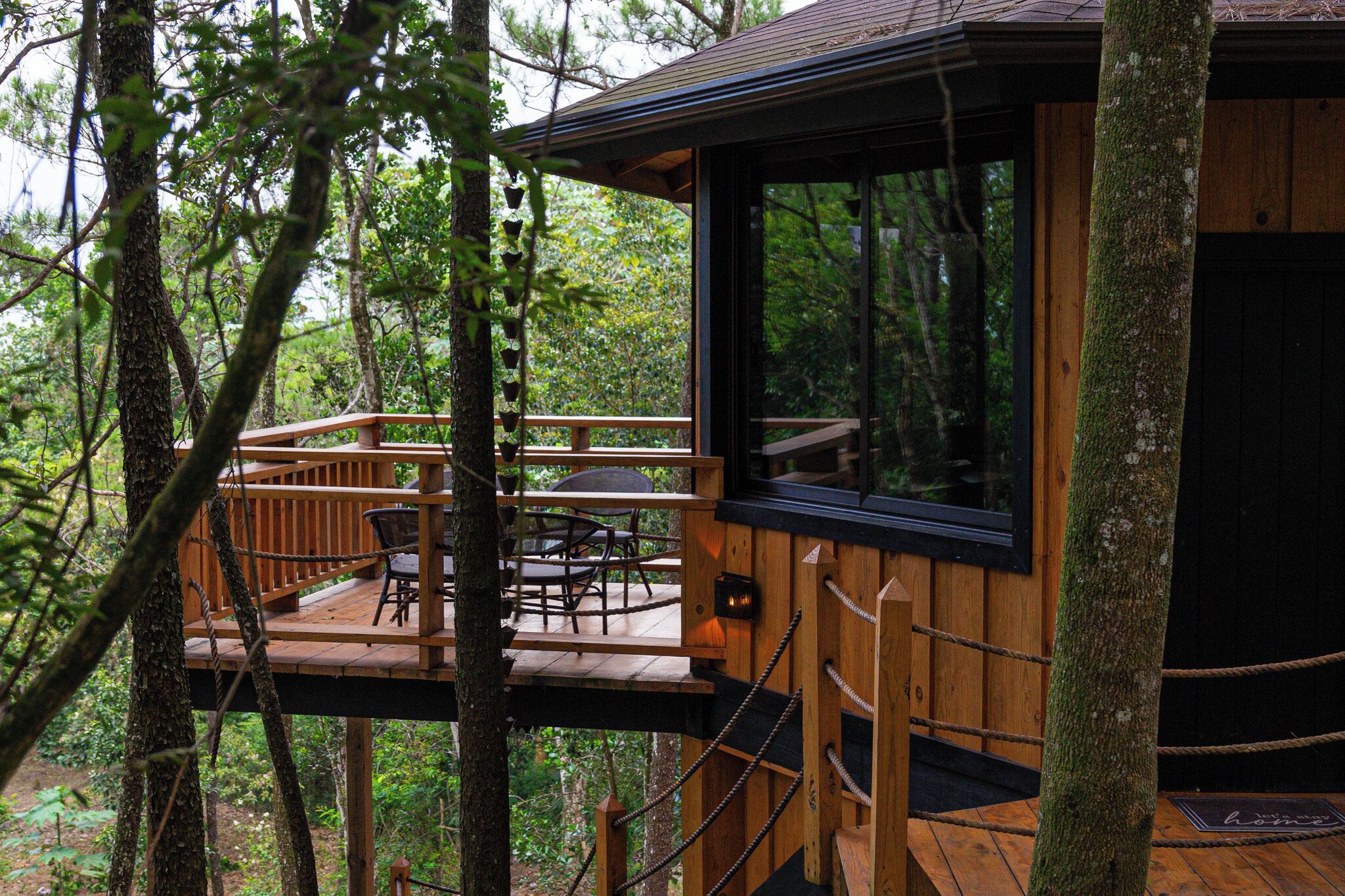 Een houten chalet met terras en eethoek, omringd door bomen.