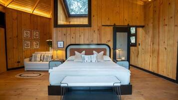 A wooden-paneled bedroom with a bed, a sofa, and a skylight.