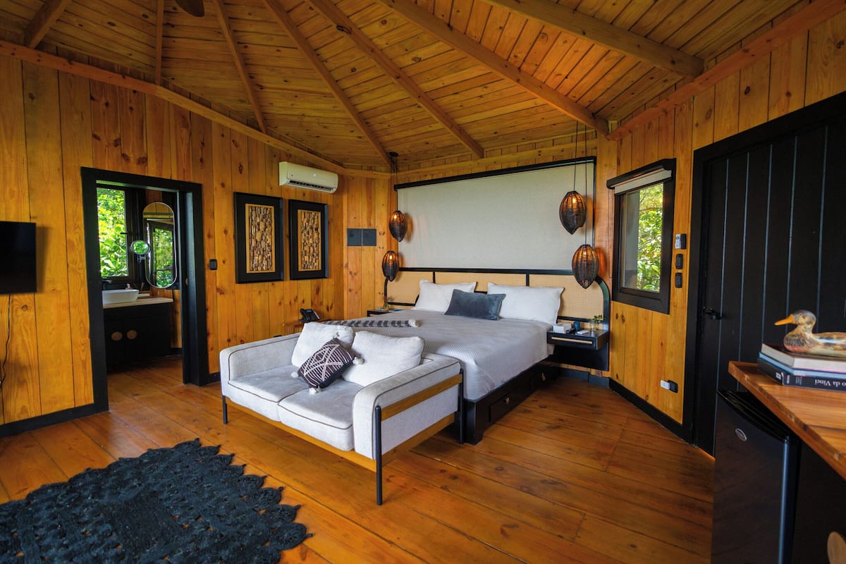 A wooden cabin bedroom with a bed, a sofa, and a desk.