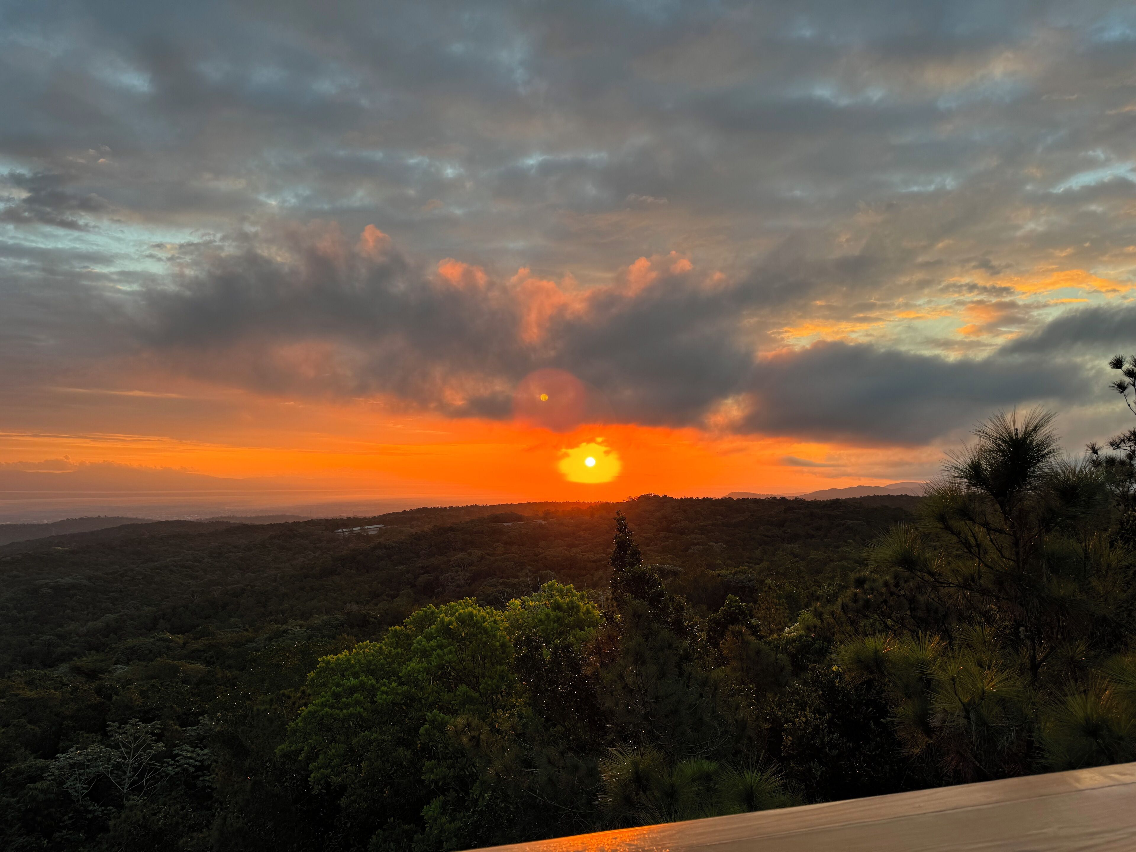 A sunset over a mountainous landscape with dense vegetation.
