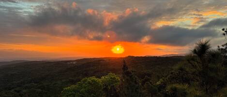 A sunset over a mountainous landscape with dense vegetation.