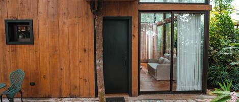 Fachada de madera con puerta de vidrio y un patio empedrado de piedra.