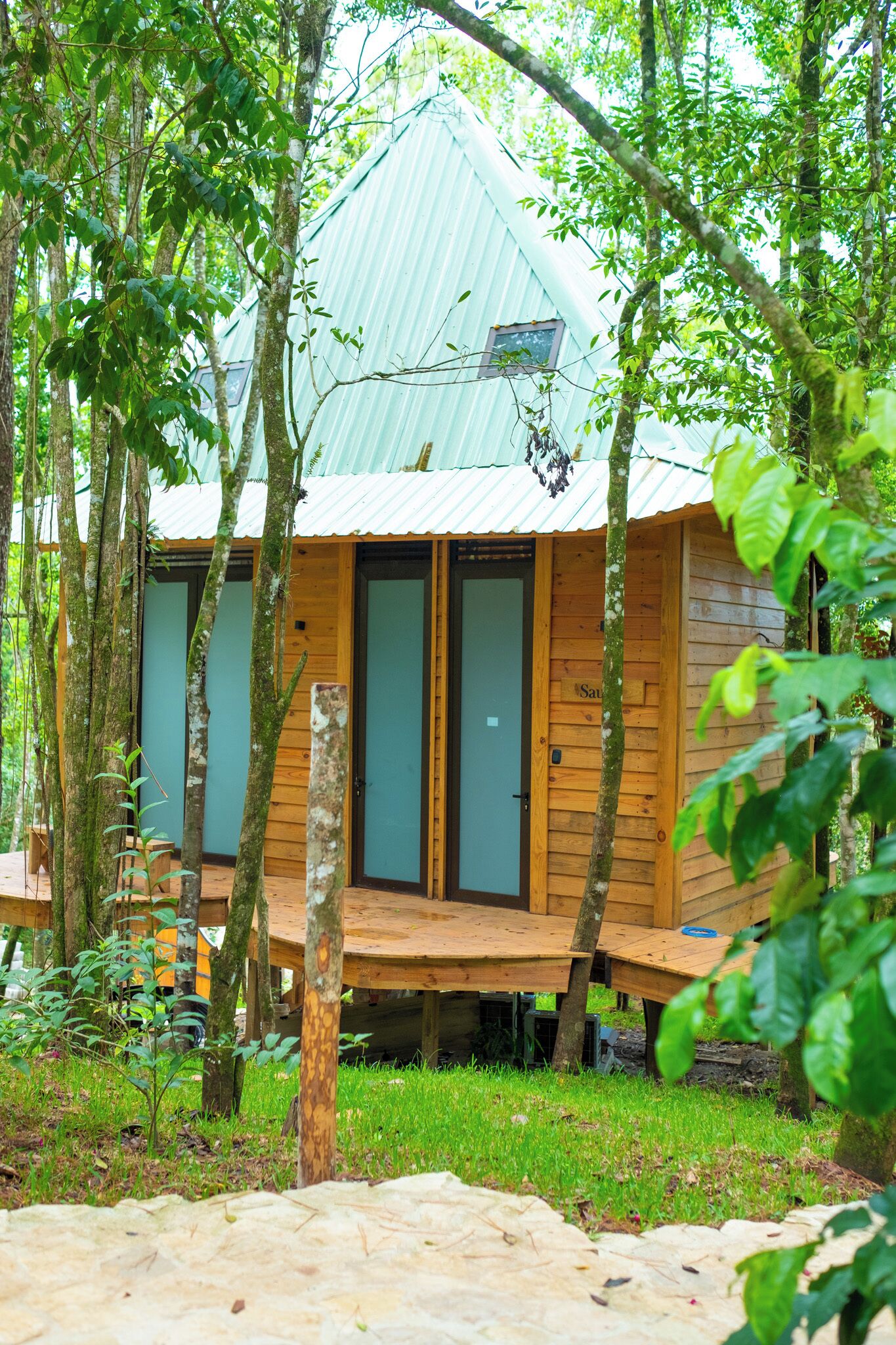 Una cabaña de madera con techo metálico, rodeada de árboles.