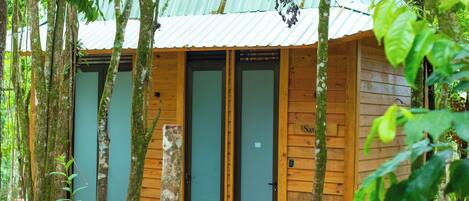 Una cabaña de madera con techo metálico, rodeada de árboles.