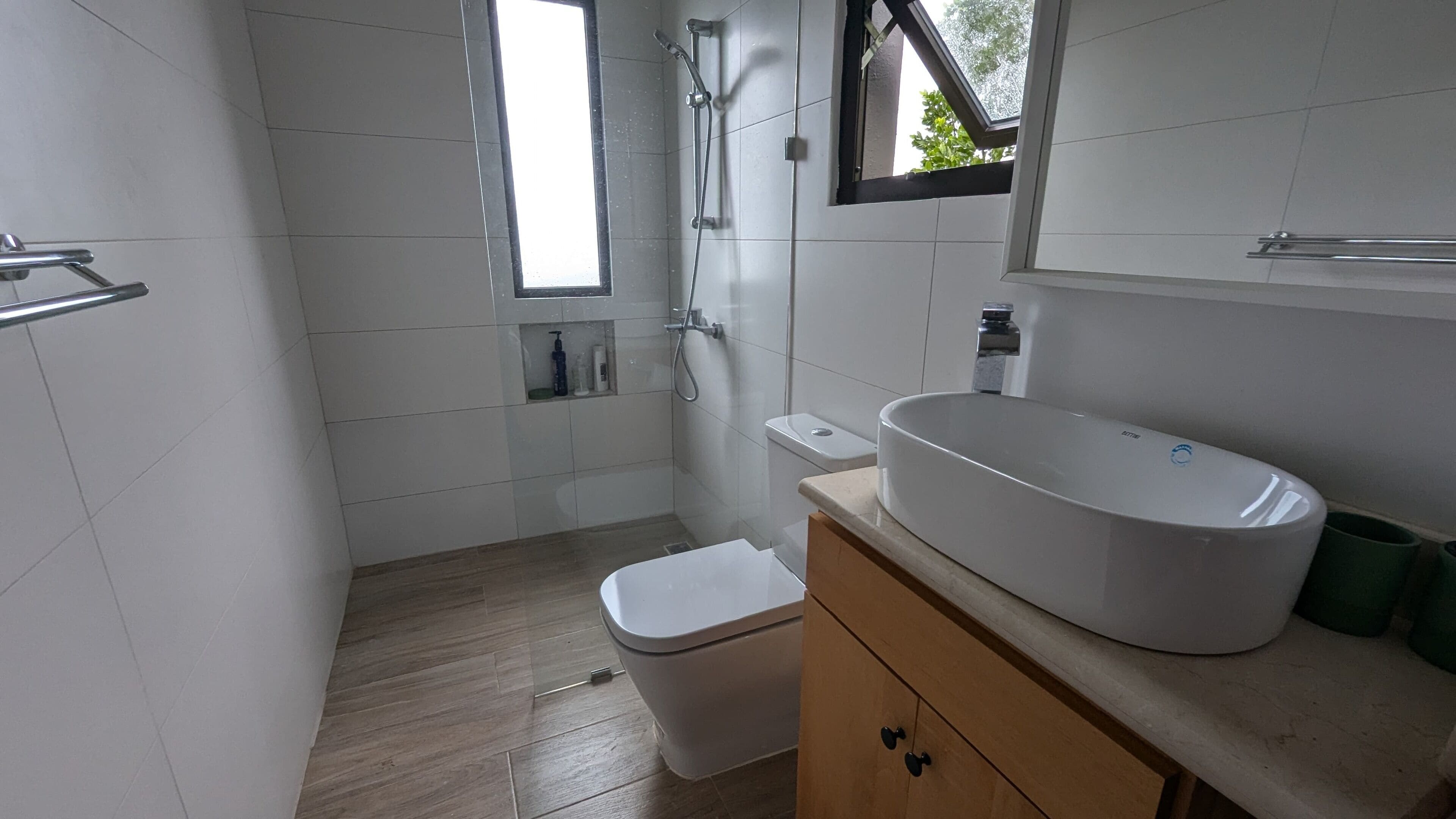 A modern bathroom with a large white sink, a toilet, and a shower area.