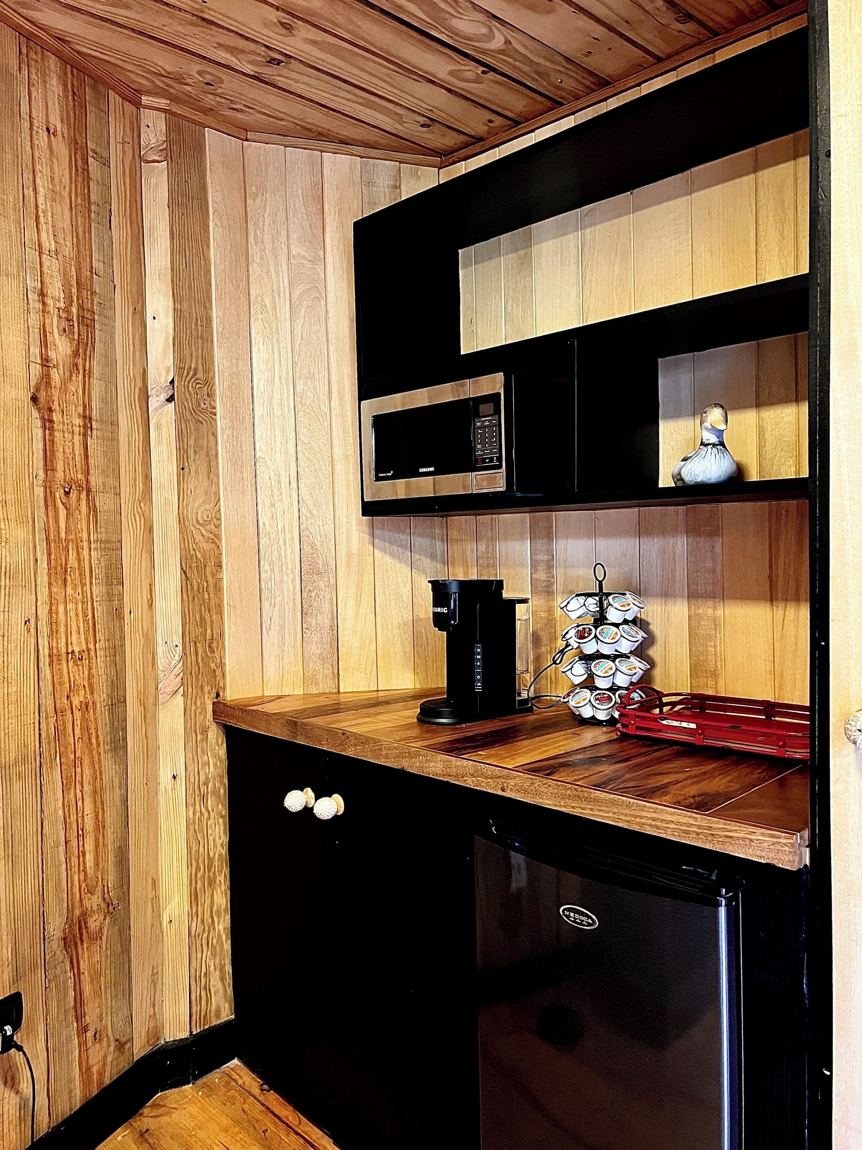 Una cocina compacta con microondas, cafetera y un refrigerador pequeño.