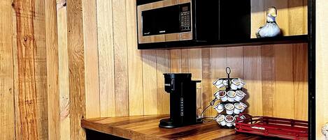 Una cocina compacta con microondas, cafetera y un refrigerador pequeño.