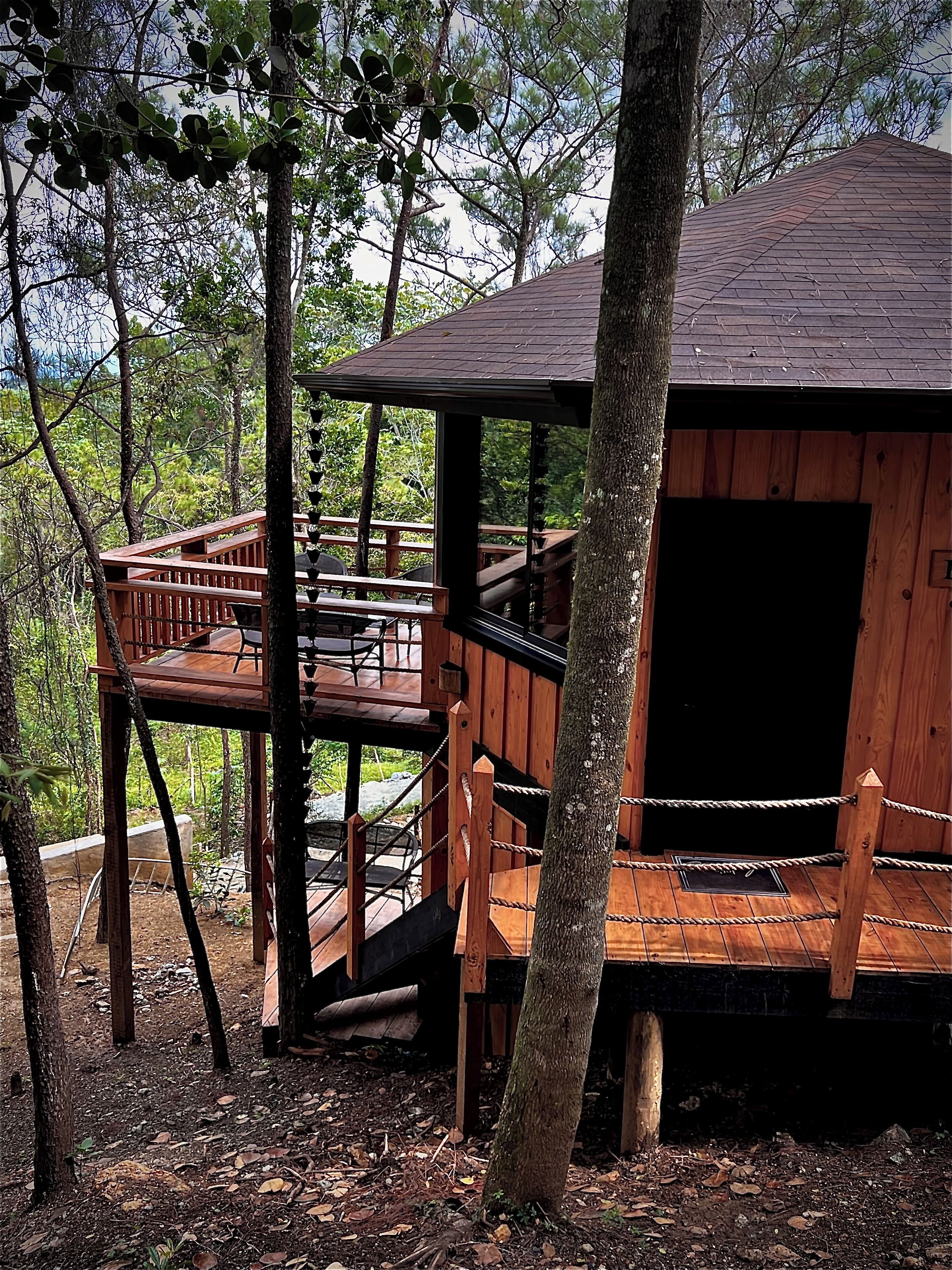 Una casa del árbol de madera con un balcón y un espacio pequeño cerrado.