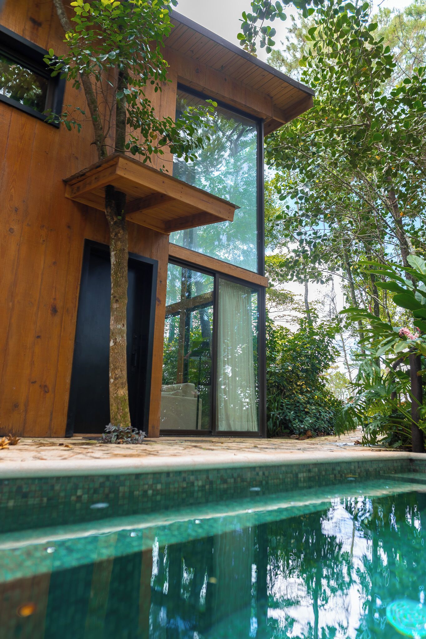 Una casa moderna con piscina, fachada de madera y grandes ventanales.