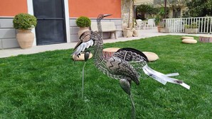 A bird sculpture in a grassy area with a building in the background.