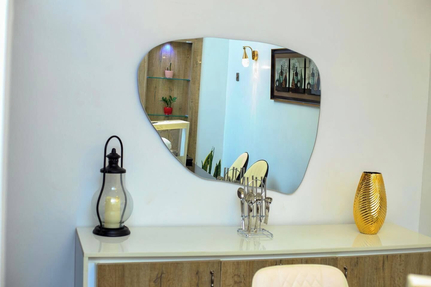Une coiffeuse avec un miroir, une bougie, un vase et un plateau contenant des articles de toilette.