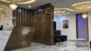 A reception area with a wooden reception desk, black leather chairs, a marble floor, and a wall with clocks and a crown logo. - Sigma Base Apartments Lagos (Lagos)