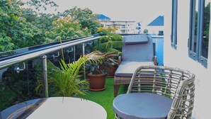 A balcony with a round table and wicker chairs, potted plants, and a hanging light fixture. - Sigma Base Apartments Lagos (Lagos)