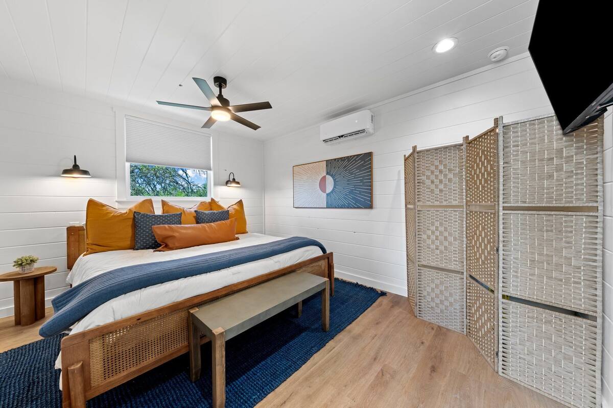 A bedroom with a bed, wooden headboard, and a ceiling fan.