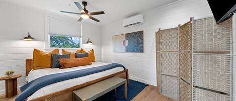 A bedroom with a bed, wooden headboard, and a ceiling fan.