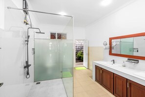 A modern bathroom with a glass shower enclosure, a large mirror, and wooden cabinets.