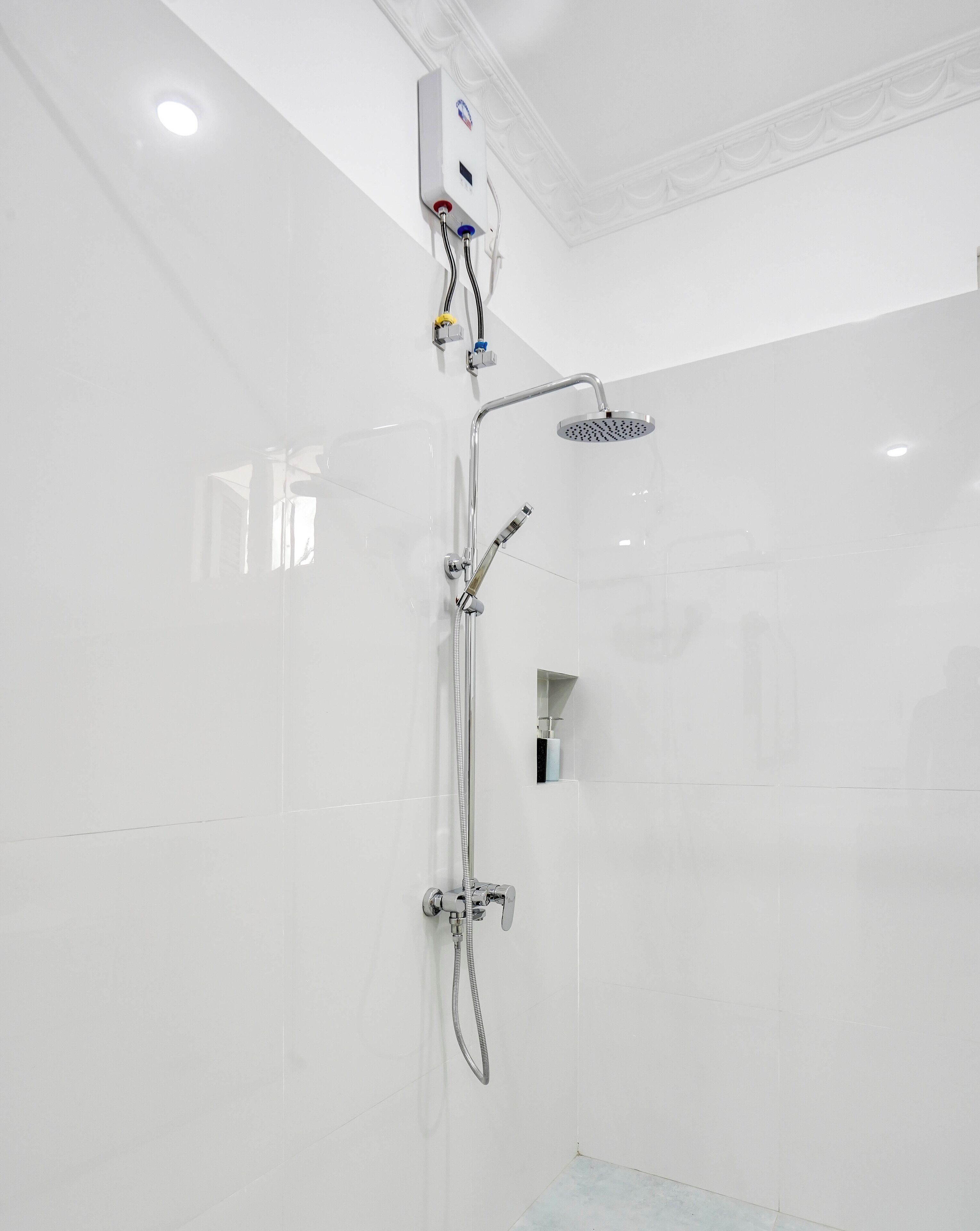 Un baño moderno con ducha a ras de suelo, cabezal de ducha manual y panel de control en la pared.