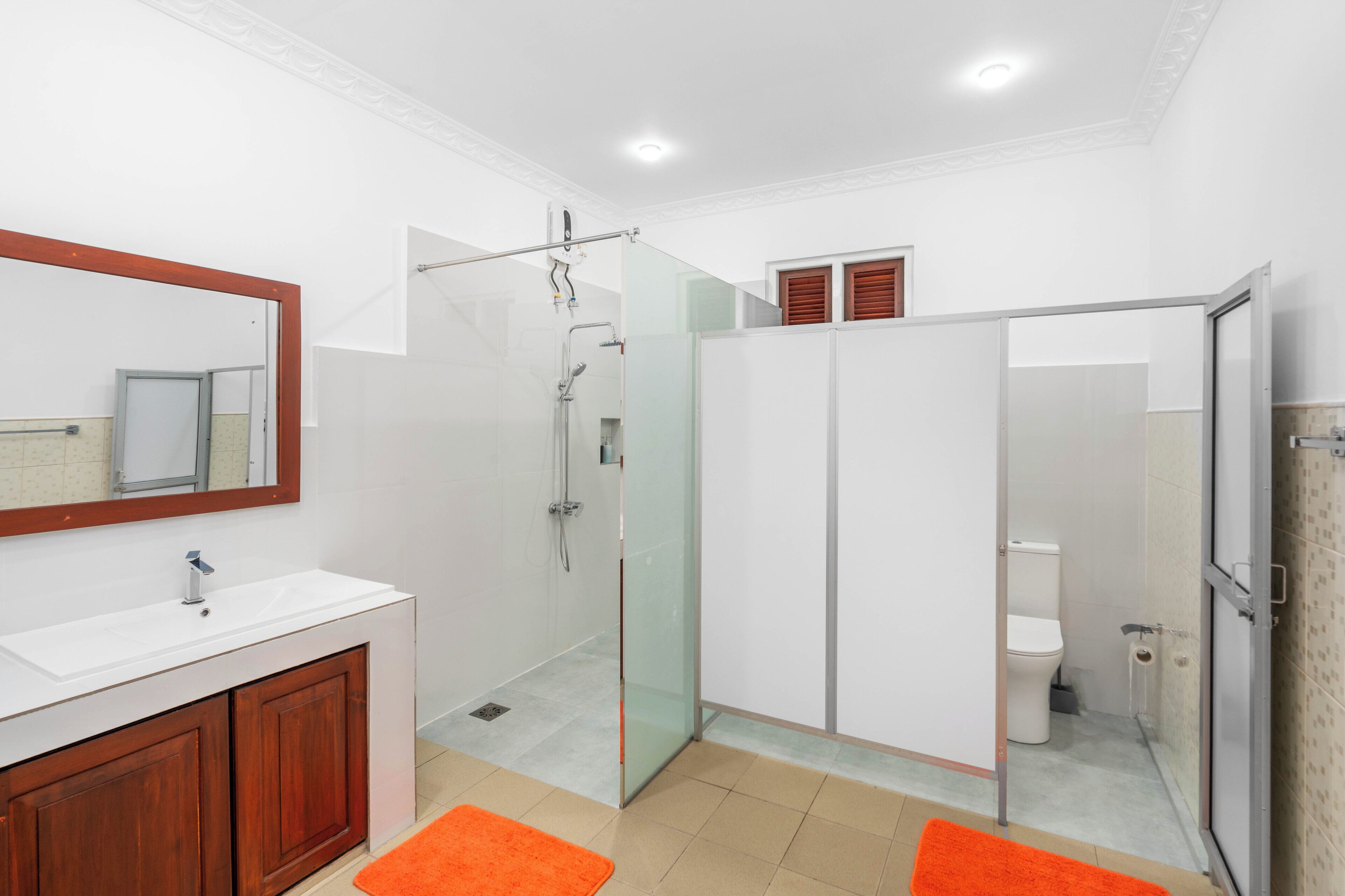 A modern bathroom with a glass shower enclosure, a white sink, and a wooden vanity.