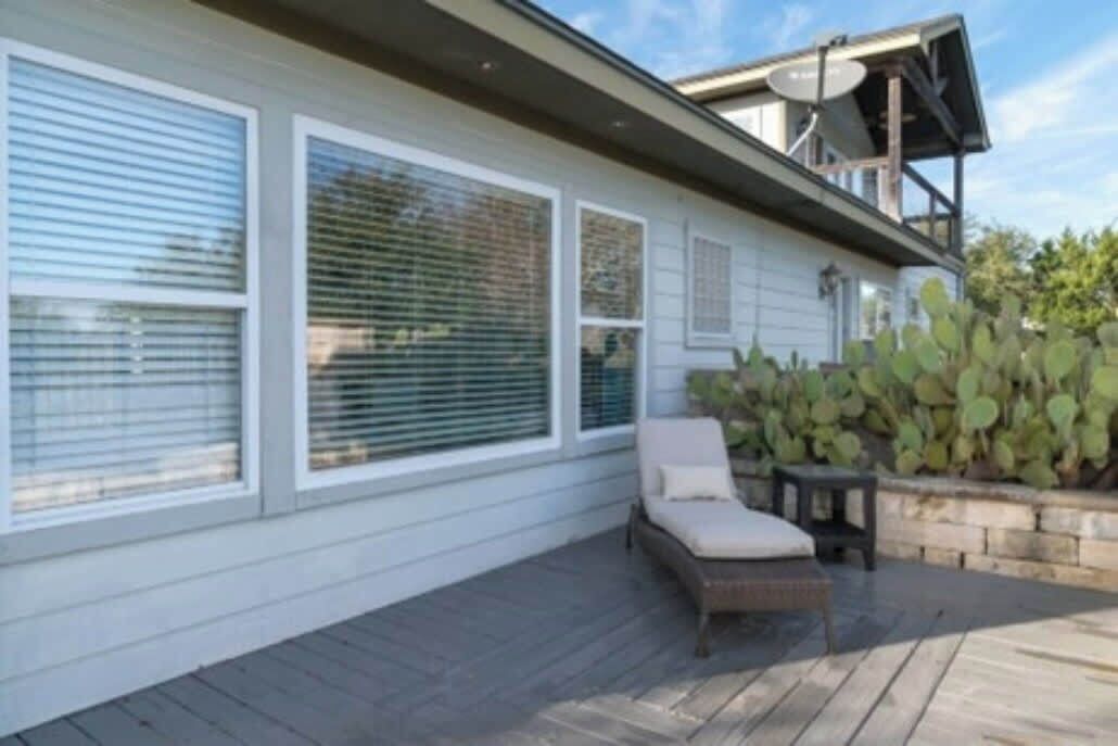 A house with a covered patio, a lounge chair, and a cactus plant.