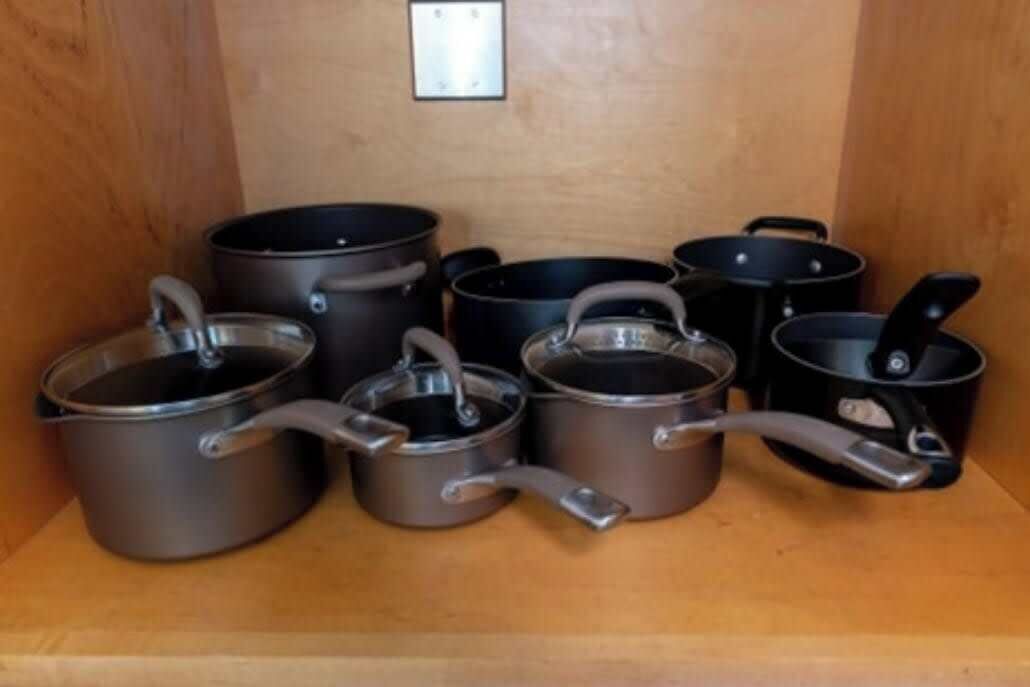 A collection of cookware on a wooden shelf.