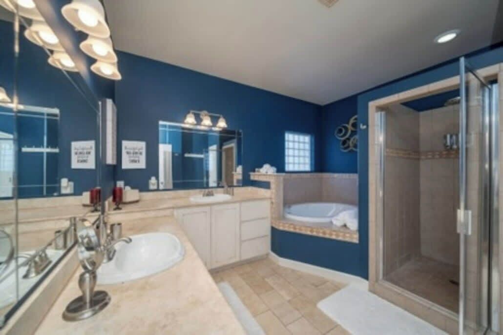 A modern bathroom with a large mirror, a bathtub, and a walk-in shower.