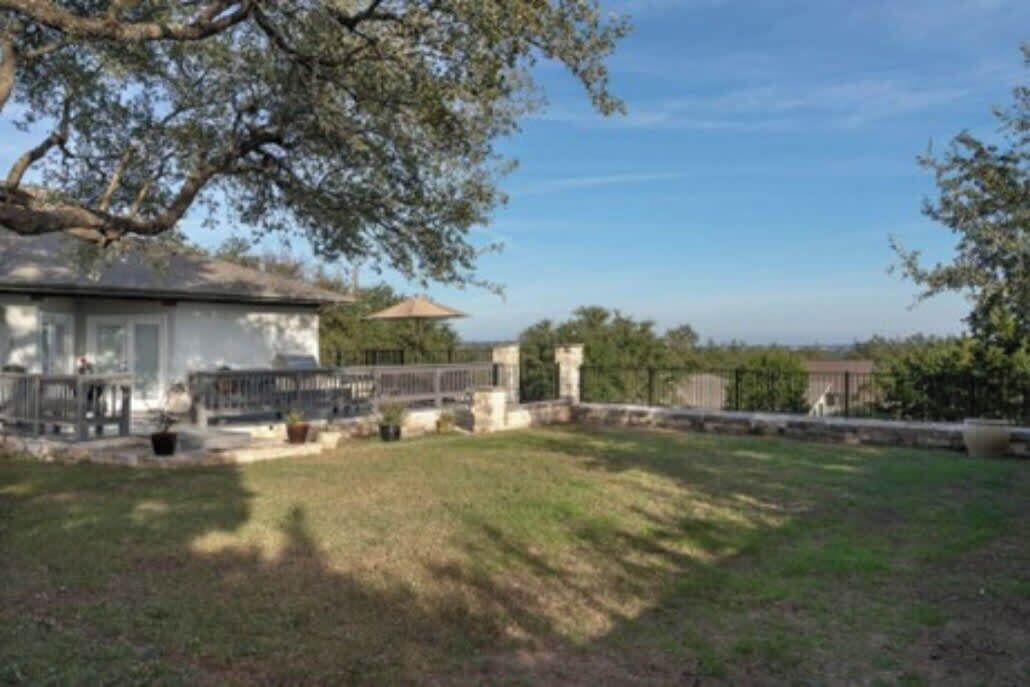 A house with a patio, a stone wall, and a grassy yard.