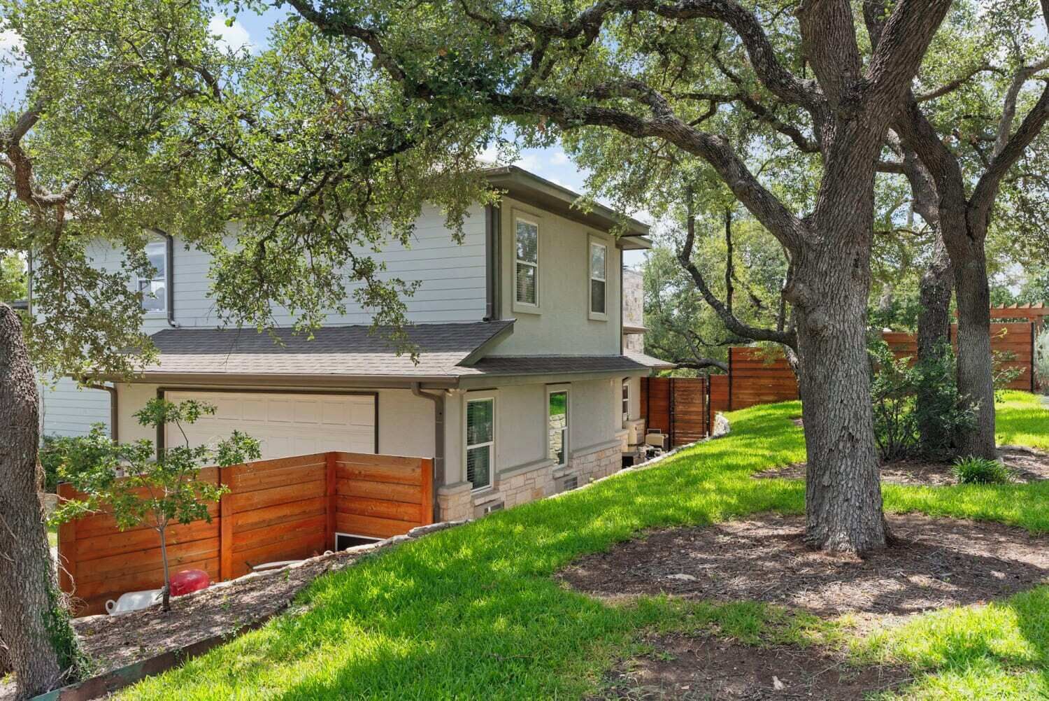 A two-story house with a garage, surrounded by trees and a well-maintained lawn.
