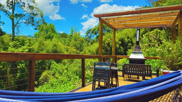 A wooden deck with a hammock, a barbecue grill, and outdoor seating.