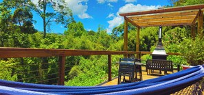 A wooden deck with a hammock, a barbecue grill, and outdoor seating. - Cores e Flores da Serra by Concavus (Santo Antonio do Pinhal)