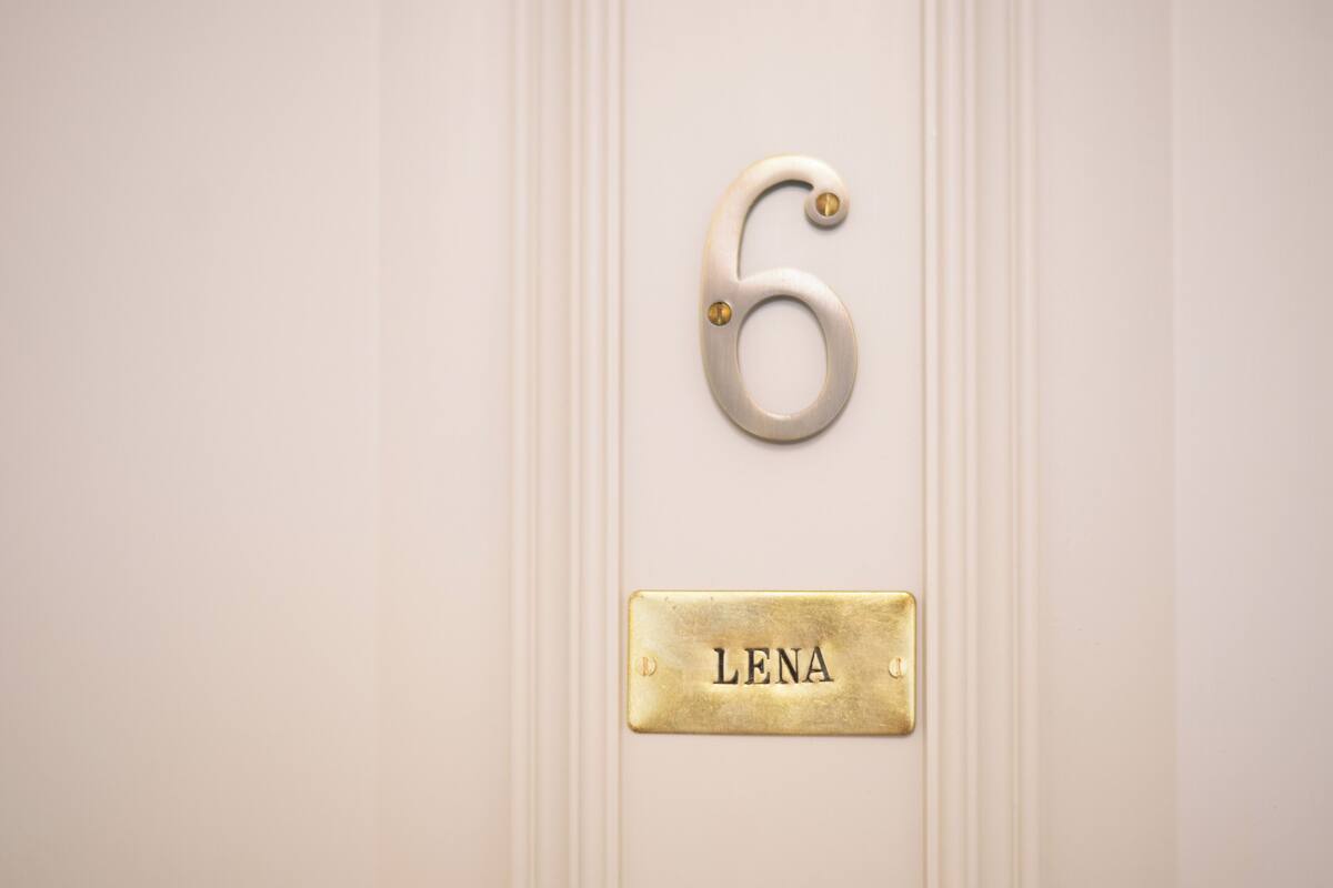A door with a brass number '6' and a nameplate 'LENA'.