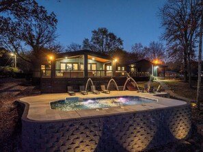 A modern house with a swimming pool, outdoor seating, and a well-lit deck area. - Lakefront! Heated Pool! Hot Tub! Game Room! (Hot Springs)