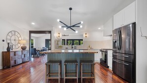 A modern kitchen with a central island, stainless steel appliances, and a wooden floor.