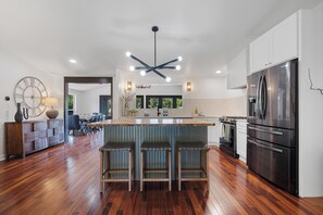 A modern kitchen with a central island, stainless steel appliances, and a wooden floor.