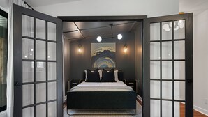 A bedroom with a bed, a painting on the wall, and two bedside lamps.