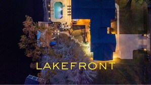 An aerial view of a house with a swimming pool, a covered patio, and a boat dock.