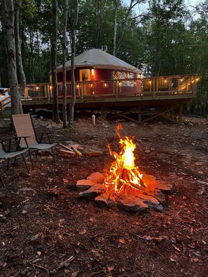 Eine Hütte mit einer Veranda und einem Feuerkorb im Vordergrund.