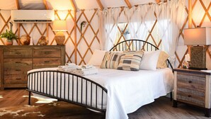 Un dormitorio acogedor con estructura metálica, ropa de cama blanca y cómoda de madera.