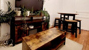 A living room with a wooden coffee table, a TV on a wooden stand, and various plants. - Large, charming apartment near Montparnasse (Paris)