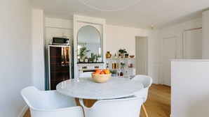 A modern kitchen with white cabinetry, a marble countertop, and a bowl of fruit on the table. - Charming quiet apartment in the heart of Paris (Paris)