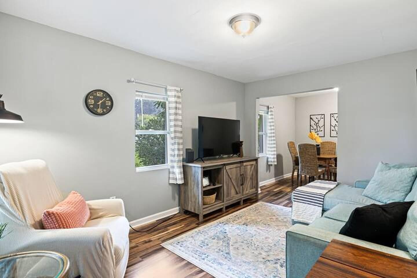 Una sala de estar con sofá, sillón, mueble para televisión y un comedor con sillas y mesa.