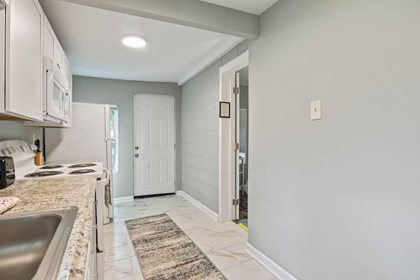 A kitchen with white cabinets, a stove, and a sink.