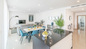 Un espace de repas moderne avec un îlot central, un canapé et un téléviseur en arrière-plan.