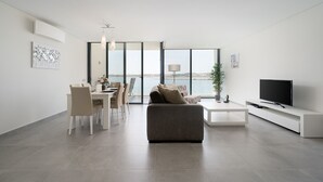 Uma sala de estar moderna com sofá, televisão, mesa de jantar e cadeiras.