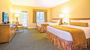 A hotel room with two beds, a television, a desk, and a chair.