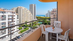 A balcony with a table and chairs, overlooking a parking area and a pool. - PRAIA DA ROCHA OCEAN VIEW WITH POOL by HOMING (Portimão)