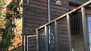 A building with a wooden exterior, a metal gate, and a staircase leading to a stone platform. - Chalet on the hill (Calvisson)