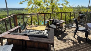 A wooden deck with outdoor furniture, a pergola providing shade, and a view of a green landscape. - Chalet on the hill (Calvisson)